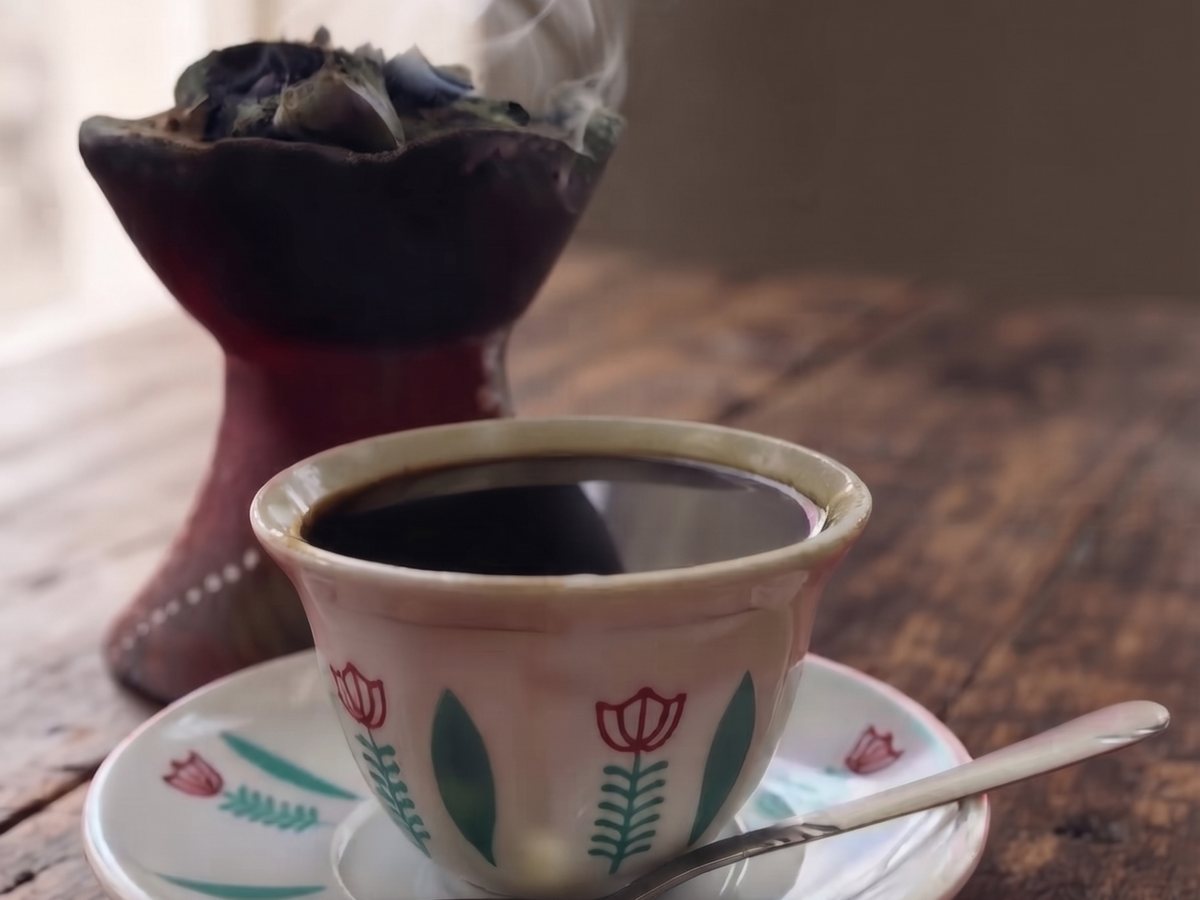 A cup of buna and the jebena beside it, on the table